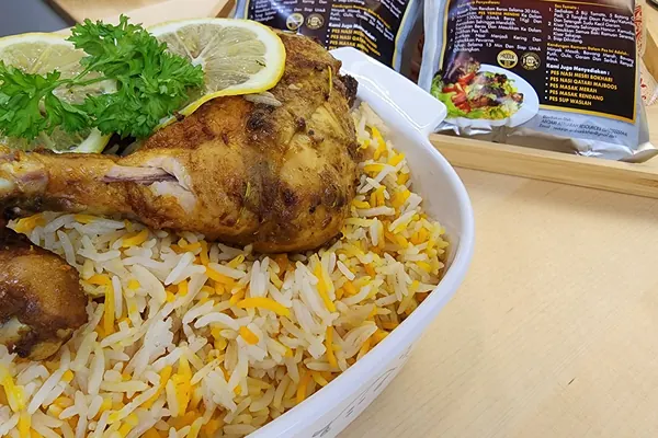 Ayam bakar dengan hirisan lemon dan daun parsley di atas nasi Yemeni Mendhi, pek pes di belakang