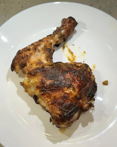Suku ayam panggang dengan kulit garing di atas pinggan putih