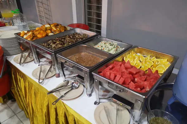 Barisan bufet dengan ayam, daging, salatah, sos dan buah dalam bekas berasingan