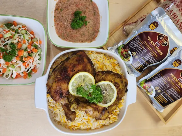 Hidangan nasi arab untuk tetamu: nasi Yemeni Mendhi dengan ayam bakar, mangkuk salad dan sos tomato, pek pes di tepi