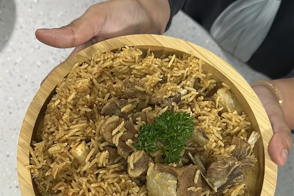 Nasi Kabsa kambing carik dalam mangkuk kayu, dimasak dalam periuk nasi, dihias daun parsley