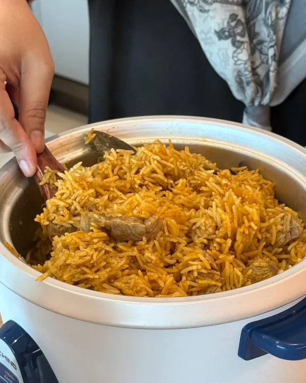 Nasi Saudi Kabsa dikacau dalam periuk nasi supaya masak sekata
